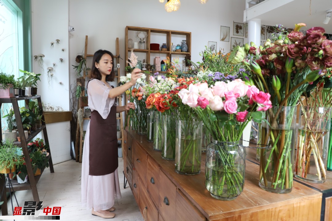 王黎媛是一名河南姑娘，在昆明念完大學后，就再也舍不下春城的藍天陽光、青山碧水，更舍不下這里的四時繁花，于是就干脆留了下來，成了一名媒體人。2017年的時候又毅然辭去工作，創(chuàng)業(yè)開起了花店，成了都市里的一名“花房姑娘”。圖為王黎媛在自己的花店中整理鮮花。新華網 周亞平/攝 念新洪/文